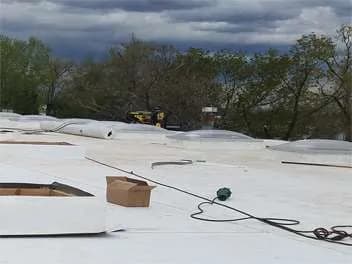 Flat white membrane roof on a commercial building under storm clouds
