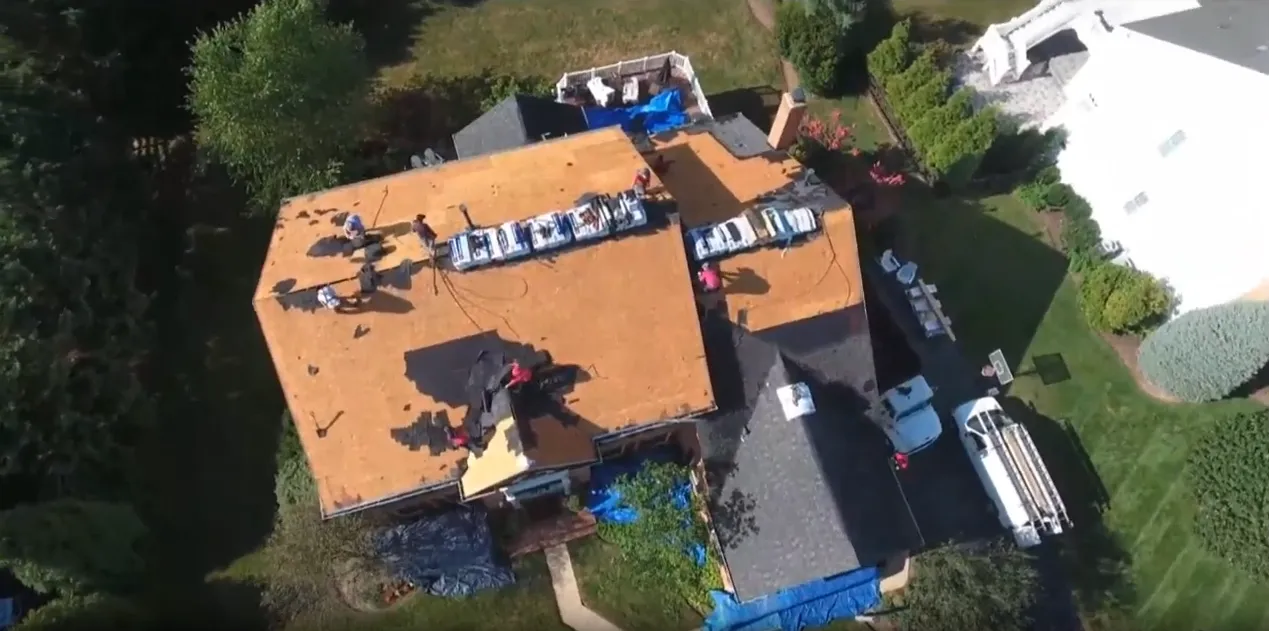 Aerial view of a Gold Star crew tearing off and re-decking a house roof
